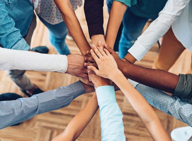 A large group of people stack hands in a circle